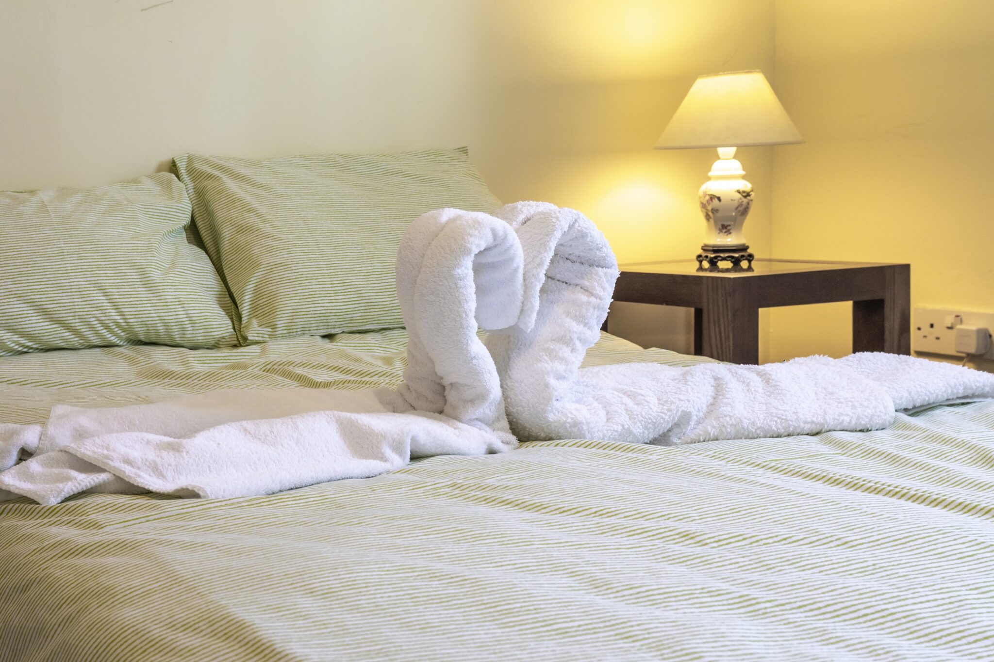 Double bedroom with crisp white linen and decorative towel swans at Pleasant Hill Scotland, Milngavie