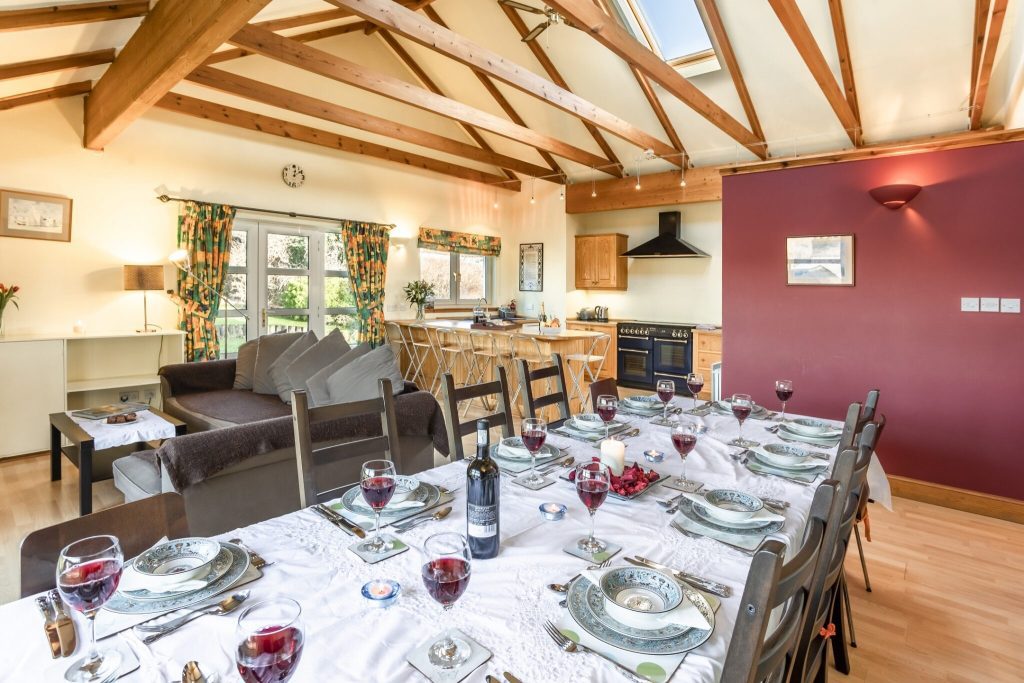 Spacious open-plan dining and kitchen area with exposed timber beams at Pleasant Hill Scotland, table set for a group dinner
